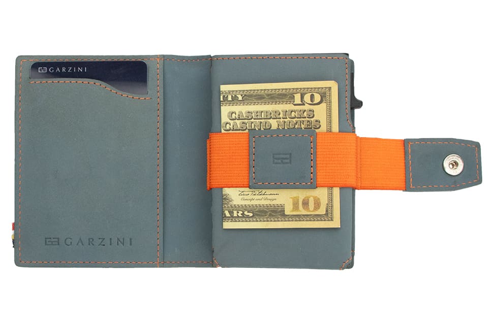 Open Garzini Metal Wallet in blue leather with orange strap, holding a stack of cash secured by the strap