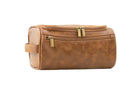 Cognac Garzini Toiletry Bag angled front side view, featuring sleek design and accessible zipper for easy travel use.